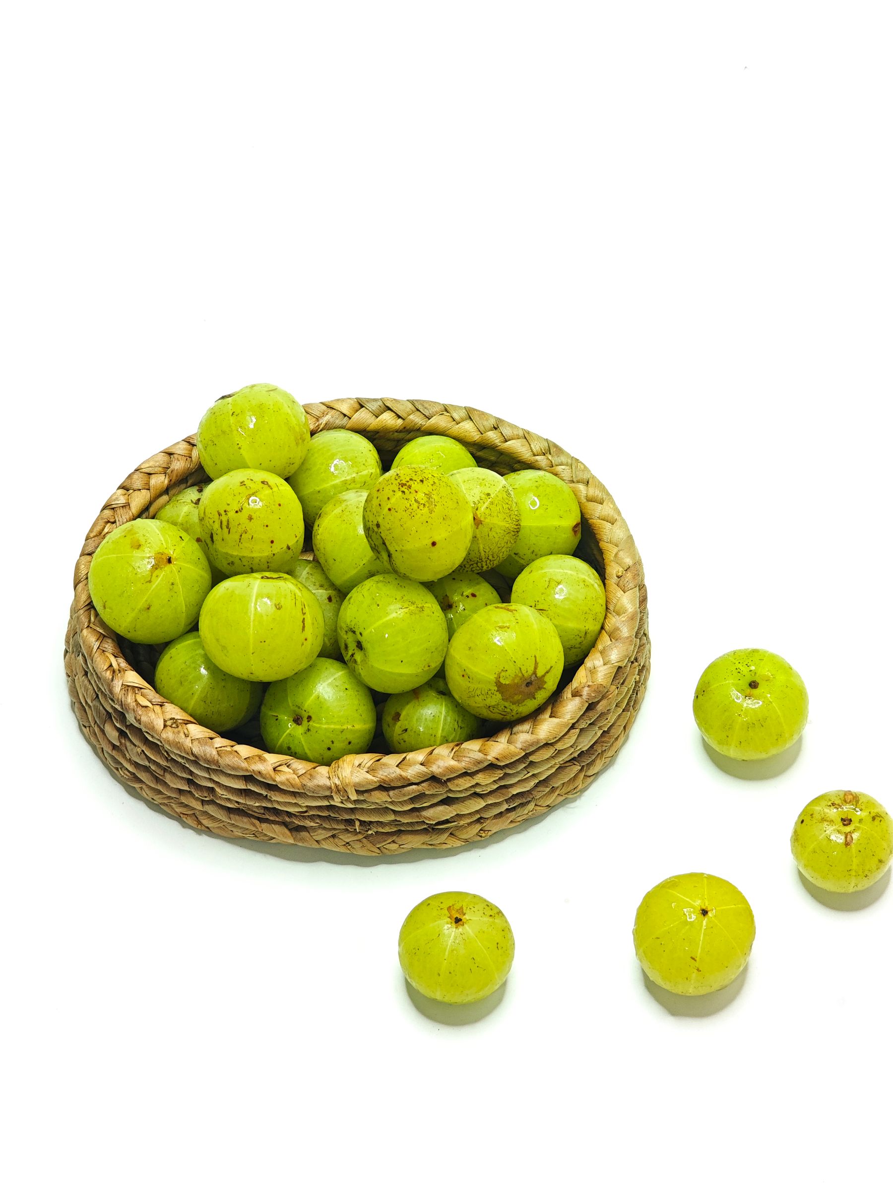 A wicker basket of fresh green amla, Indian gooseberries